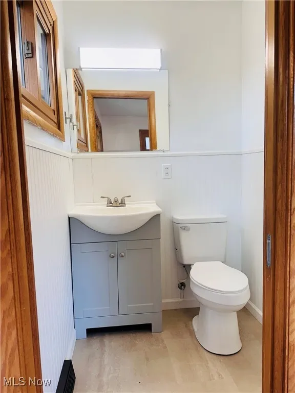 Half bathroom featuring vanity and wainscoting
