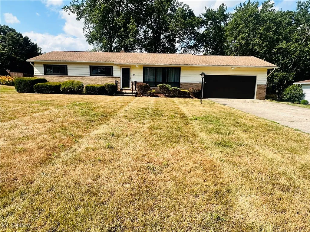 Single story home featuring a garage, concrete driveway, a front lawn, and entry steps
