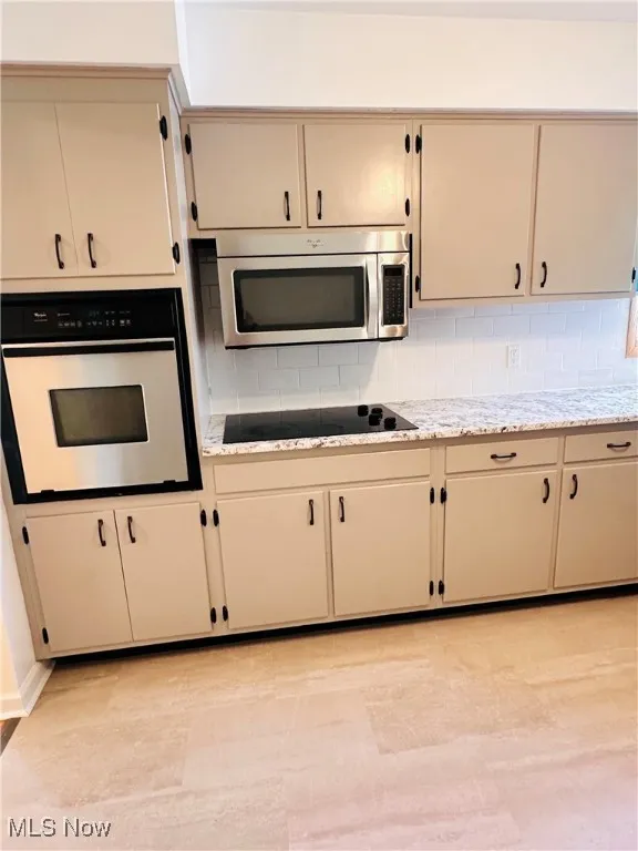 Kitchen with appliances with stainless steel finishes, tasteful backsplash, and cream cabinets
