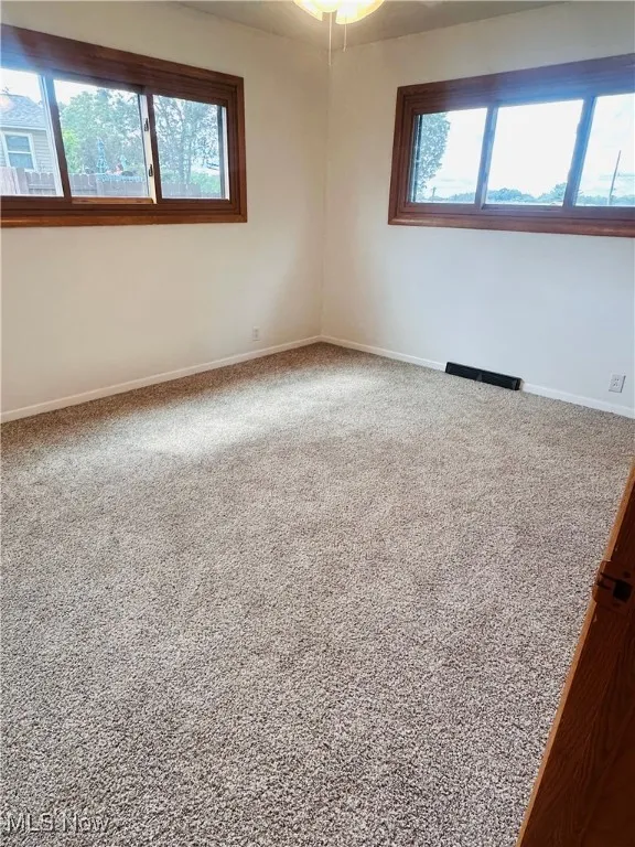 Spare room featuring carpet flooring and baseboards