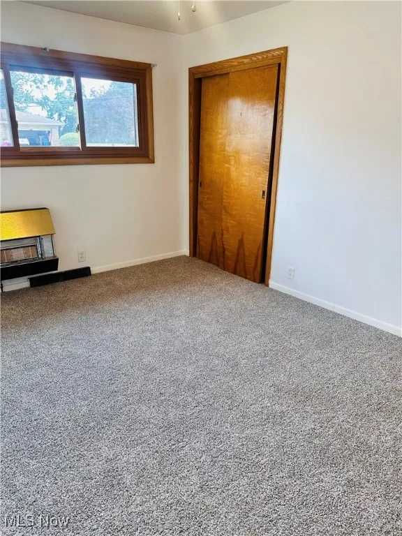 Carpeted spare room featuring baseboards