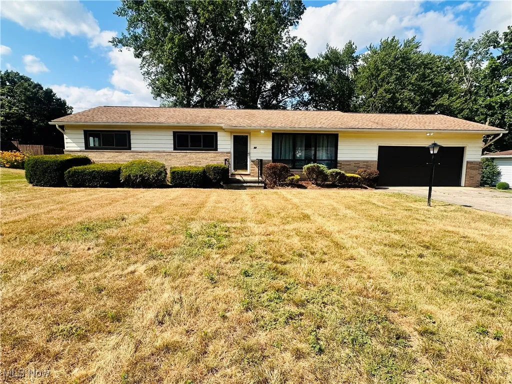Single story home featuring an attached garage, a front lawn, and concrete driveway