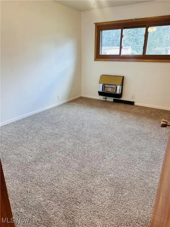 Carpeted empty room featuring baseboards