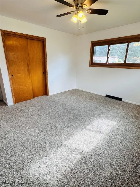 Empty room with ceiling fan and carpet