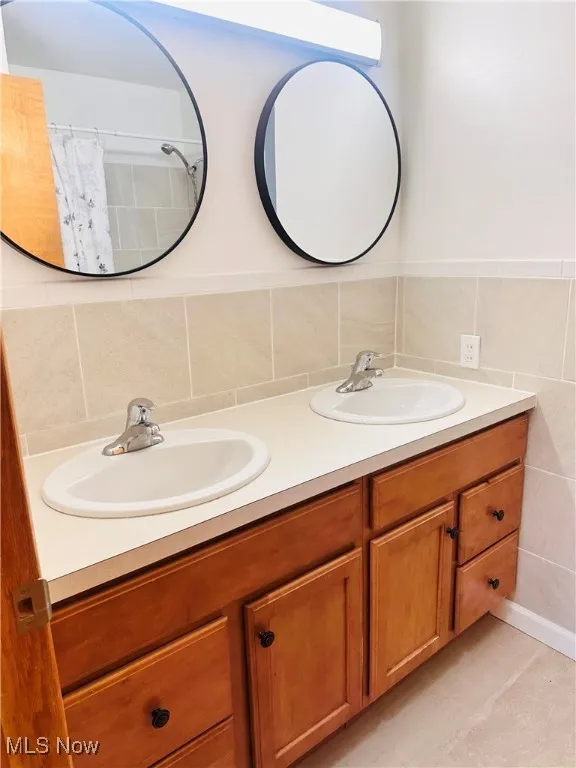 Full bath featuring double vanity and curtained shower