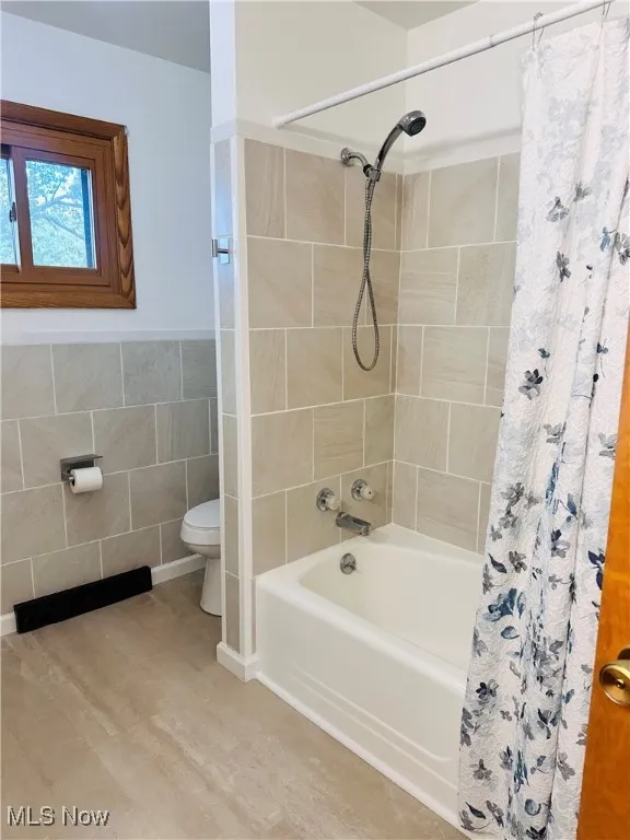 Full bathroom with shower / tub combo with curtain, tile walls, and tile patterned floors