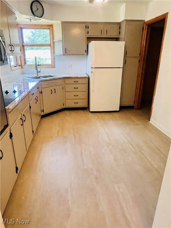 Kitchen with freestanding refrigerator, tasteful backsplash, cream cabinets, black electric stovetop, and stainless steel microwave
