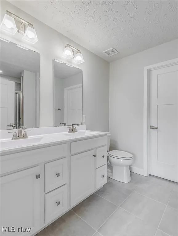 Primary bathroom has double vanity / sinks, special lighting, walk-in shower and commode