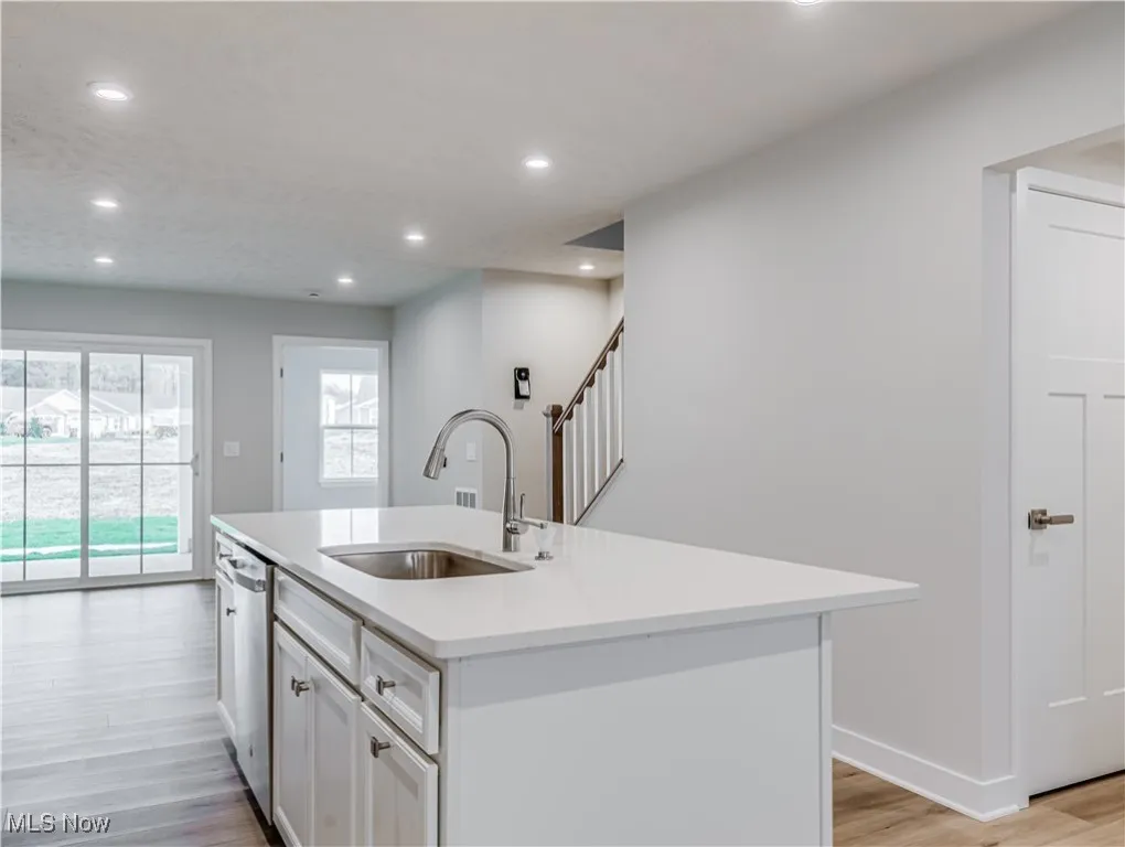 Open kitchen with island has a sink and new stainless steel dishwasher. Dining area with sliding glass door to patio