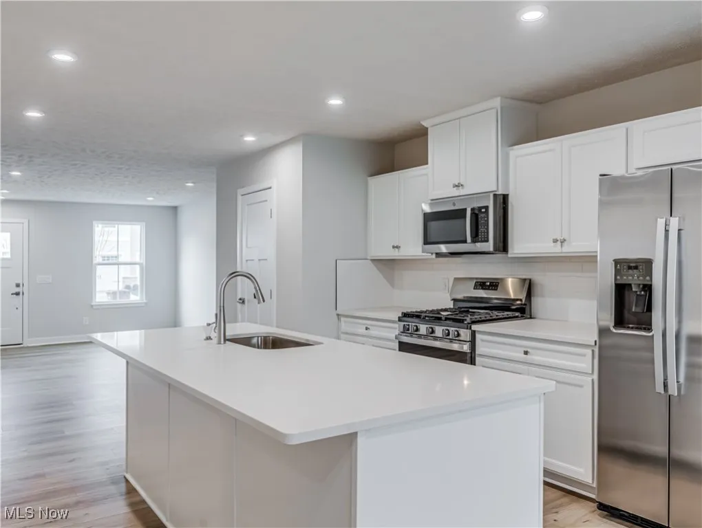 Kitchen has a breakfast bar, white cabinetry and all new stainless stee appliances