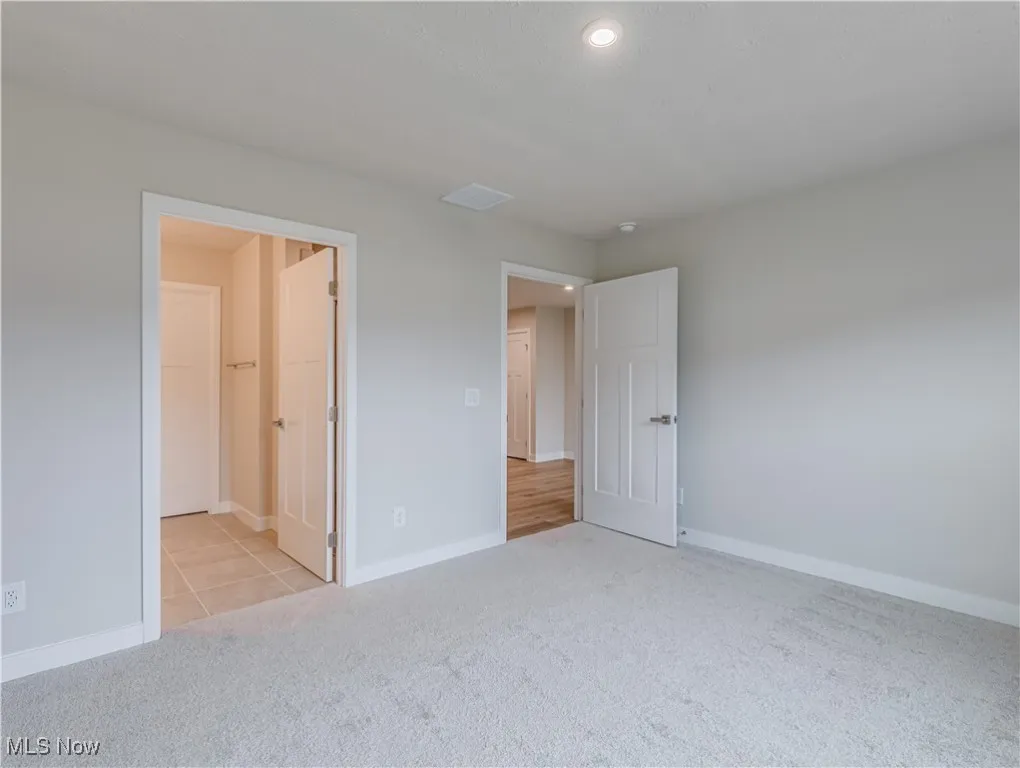 First floor primary bedroom with carpet flooring and entry into the primary bathroom