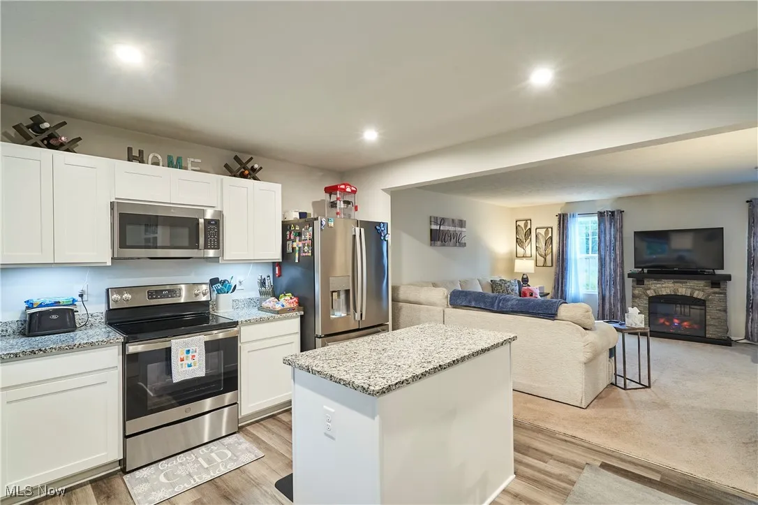 Kitchen with appliances with stainless steel finishes, open floor plan, white cabinetry, a kitchen island, and recessed lighting