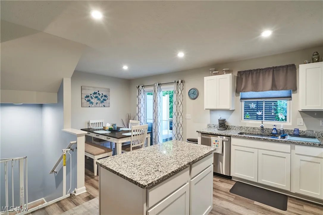 Kitchen featuring light wood-style flooring, a center island, stainless steel dishwasher, recessed lighting, and light stone counters