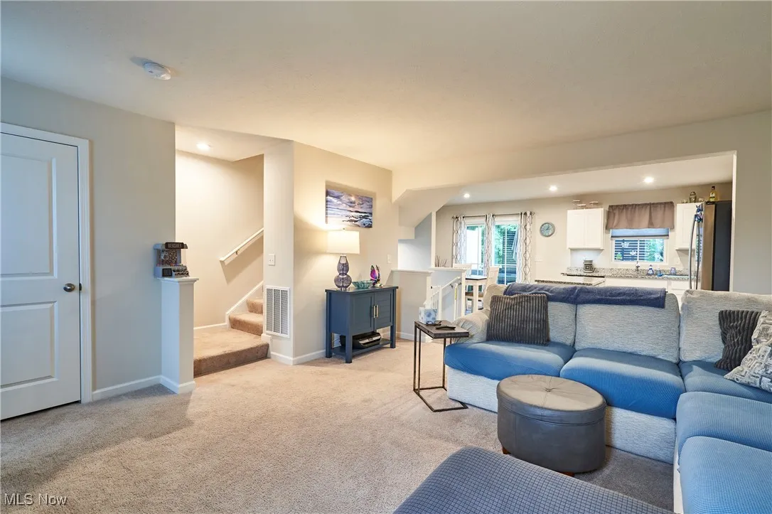 Living room featuring light carpet, recessed lighting, and stairs