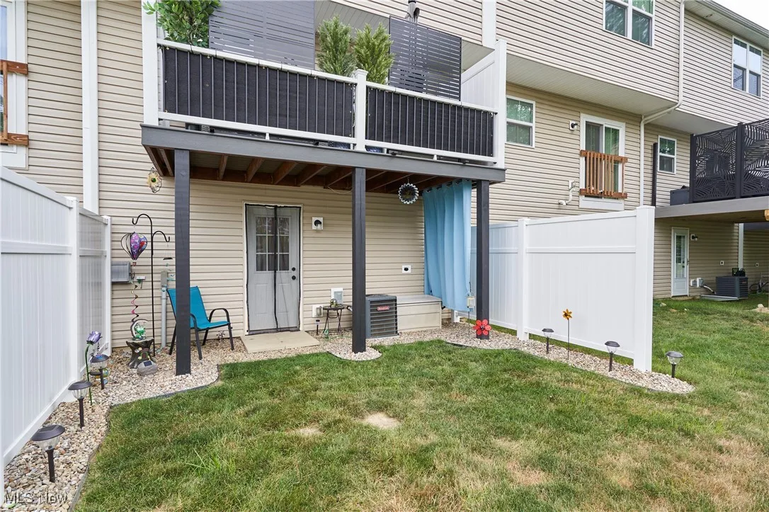 Rear view of property featuring a balcony and a fenced backyard