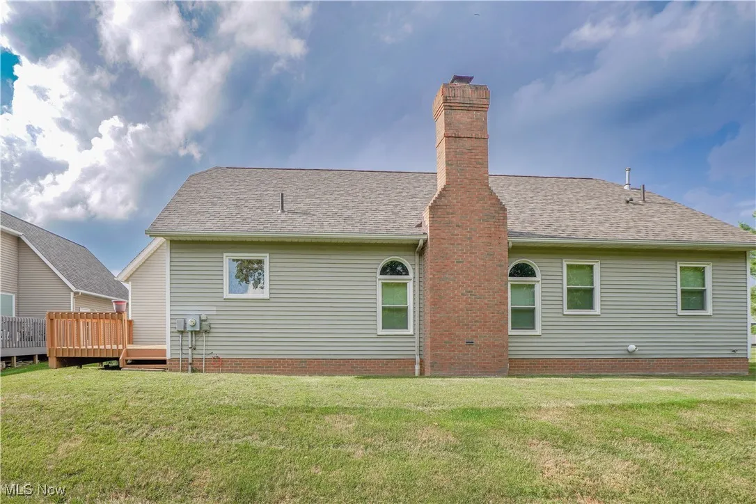 Rear view of property with a yard, a chimney, and a wooden deck