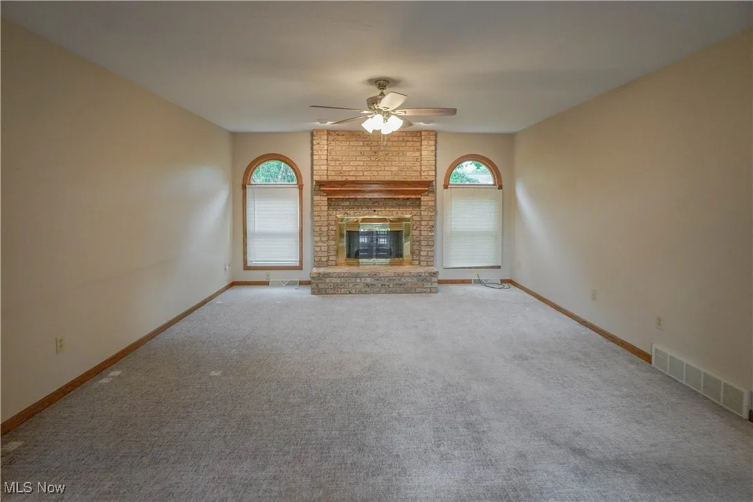 Great Room/living room with a ceiling fan, carpet, and a brick fireplace