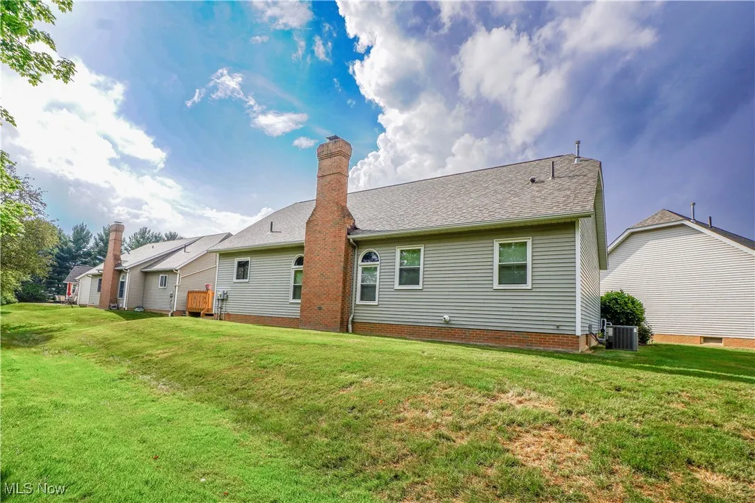 Rear view of property with a lawn, a chimney, and roof with shingles