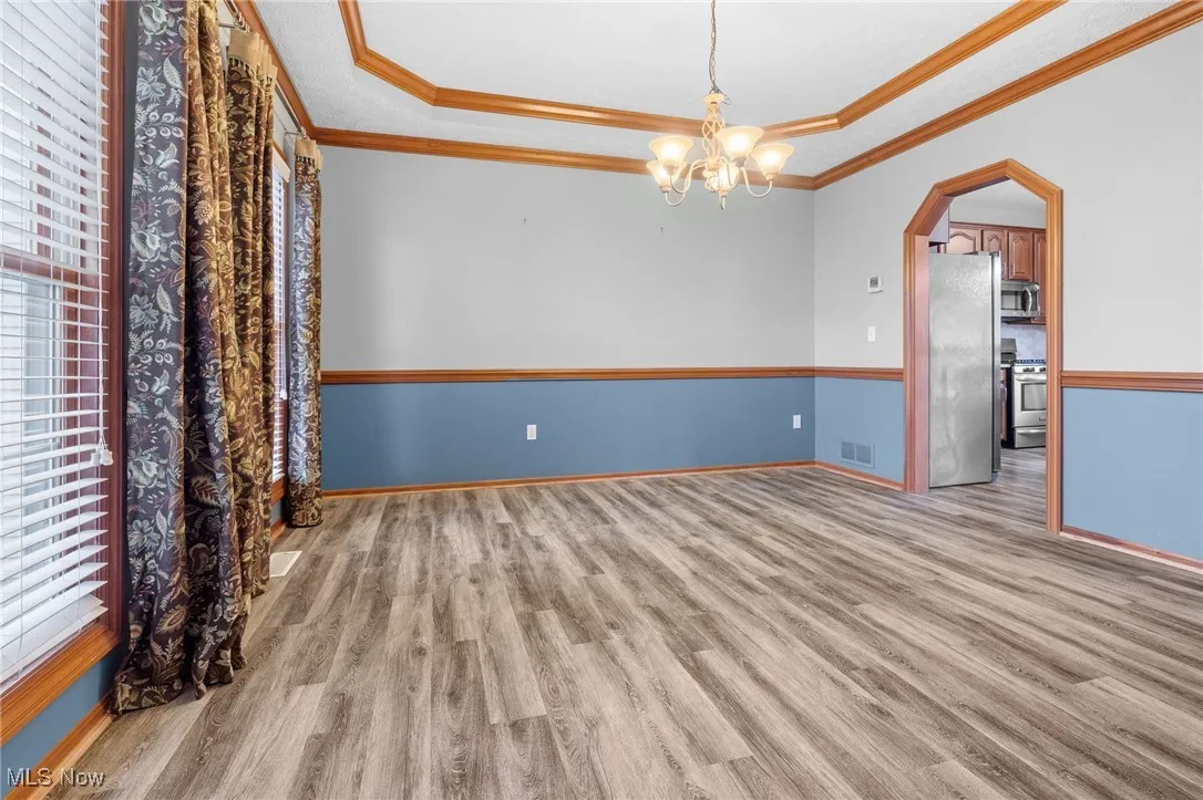 Dining room with LVT flooring, crown molding, and a chandelier
