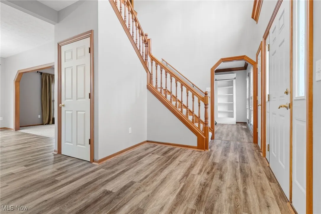 Entryway featuring light wood LVT flooring, office and/or living room with built-ins