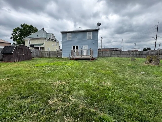 Back of house featuring a storage unit, a fenced backyard, and a deck