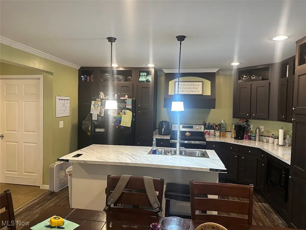 Kitchen featuring freestanding refrigerator, crown molding, light stone counters, electric range, and dark wood-style floors
