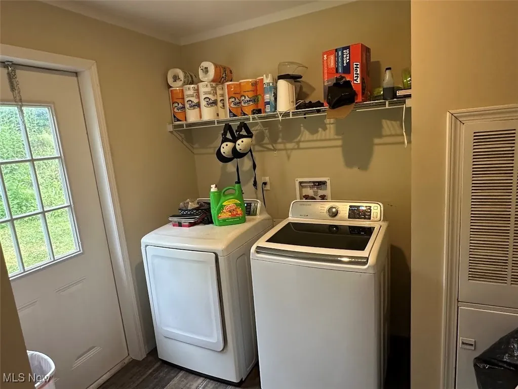 Washroom with washer and dryer, healthy amount of natural light, a heating unit, dark wood finished floors, and ornamental molding