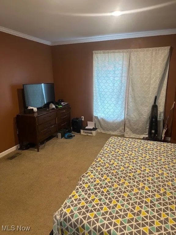 Carpeted bedroom with ornamental molding