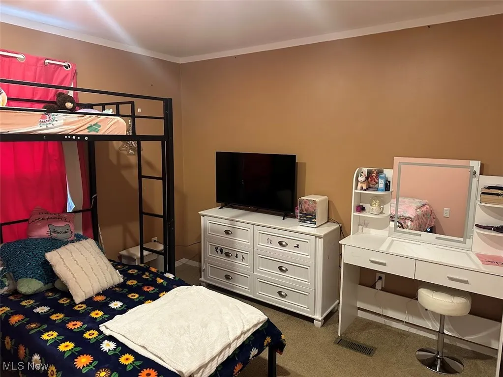 Carpeted bedroom featuring crown molding