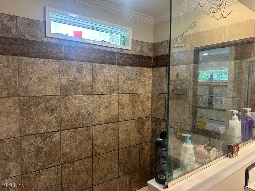 Bathroom with ornamental molding and walk in shower