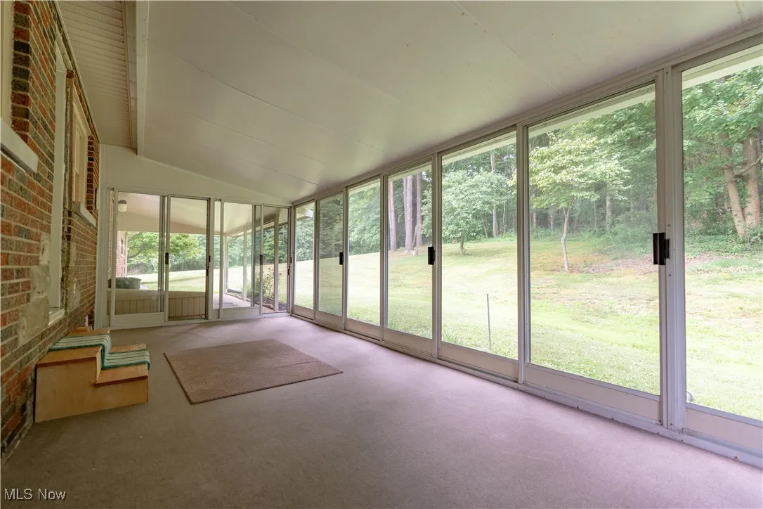 Unfurnished screened in sunroom featuring lofted ceiling
