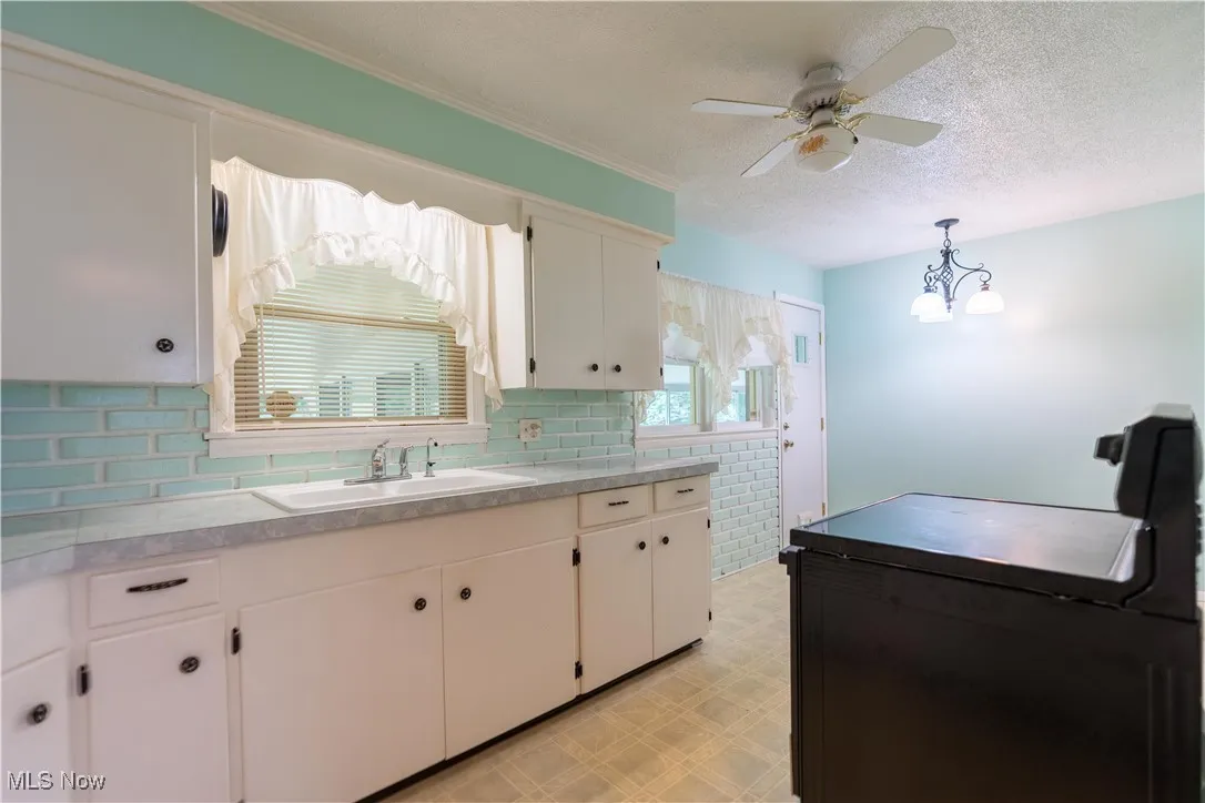 Kitchen featuring light floors, a ceiling fan, a textured ceiling, white cabinets, and light countertops