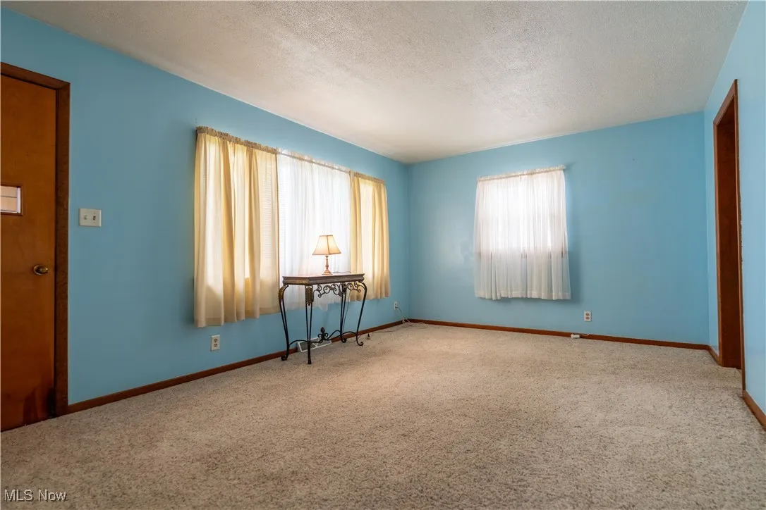 Carpeted living room featuring a textured ceiling and baseboards