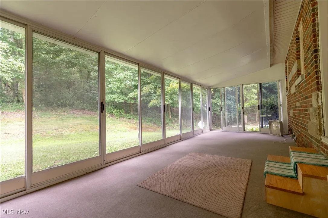 Unfurnished screened in sunroom featuring lofted ceiling