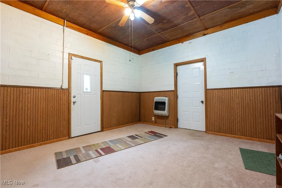 Breezeway with ceiling fan, heating unit, and light carpet