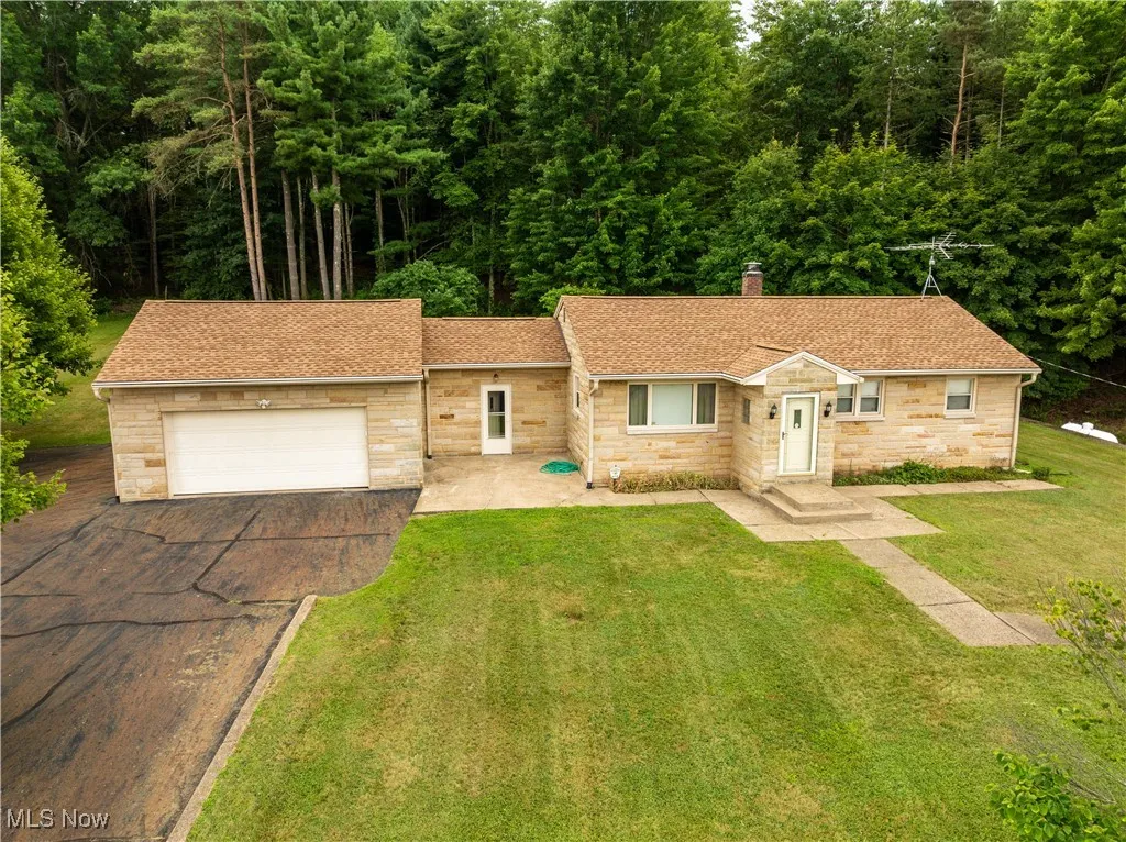 Ranch-style home with roof with shingles, asphalt driveway, stone siding, and an attached garage
