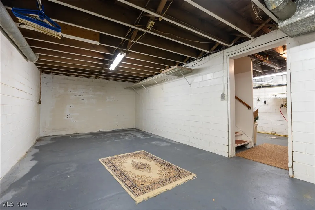 Unfinished below grade area with stairs and concrete block wall