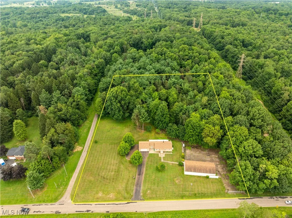 Aerial view of property and surrounding area with a heavily wooded area and property boundaries highlighted