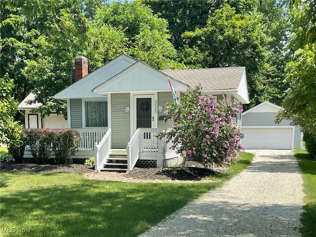 View of front of home with covered porch, an outbuilding, a chimney, new roof, and front yard
