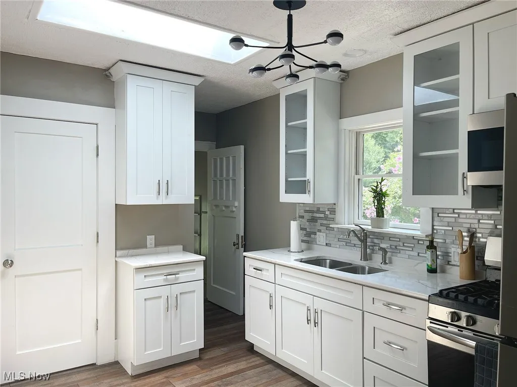 Remodeled kitchen with white cabinets, quartz countertops and stainless steel appliances.