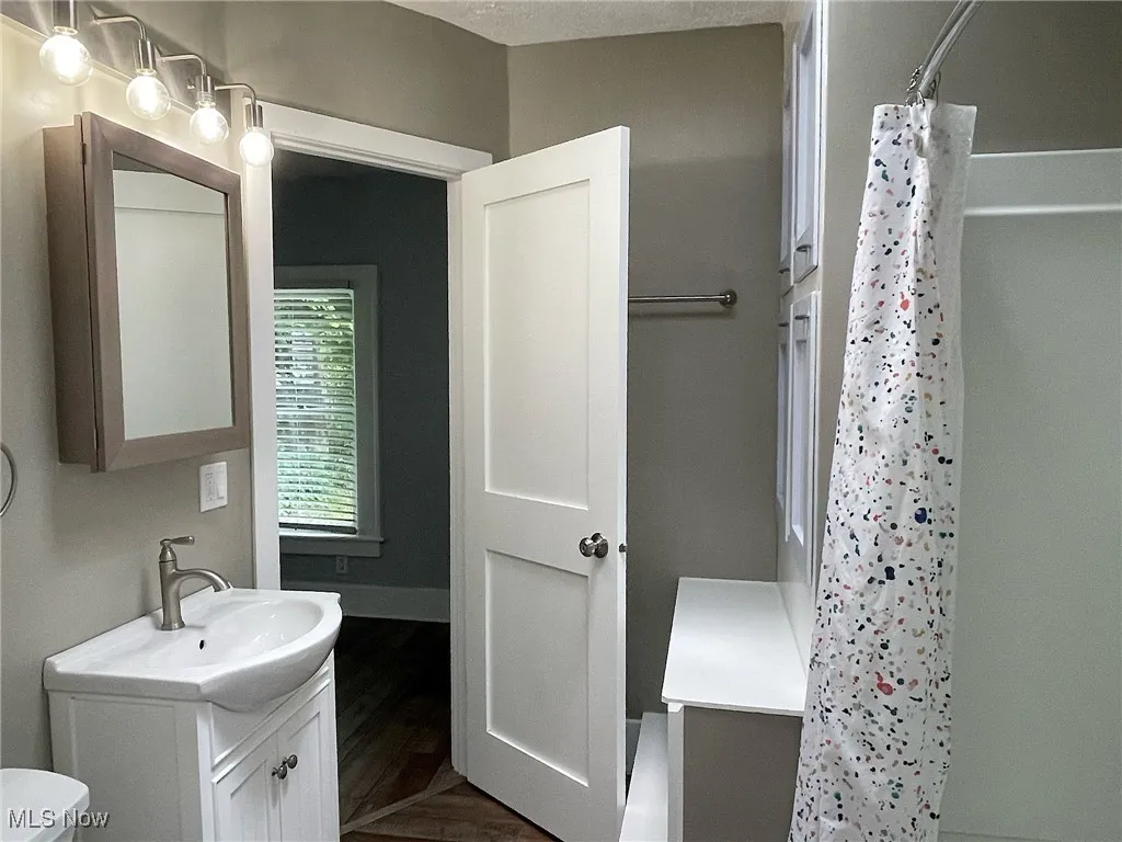 Bathroom with vanity,  floors, and curtained shower