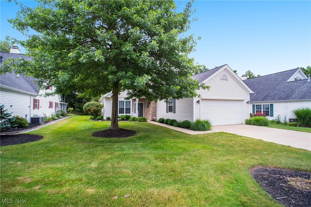 View of front of property featuring concrete driveway, an attached garage, and a front lawn