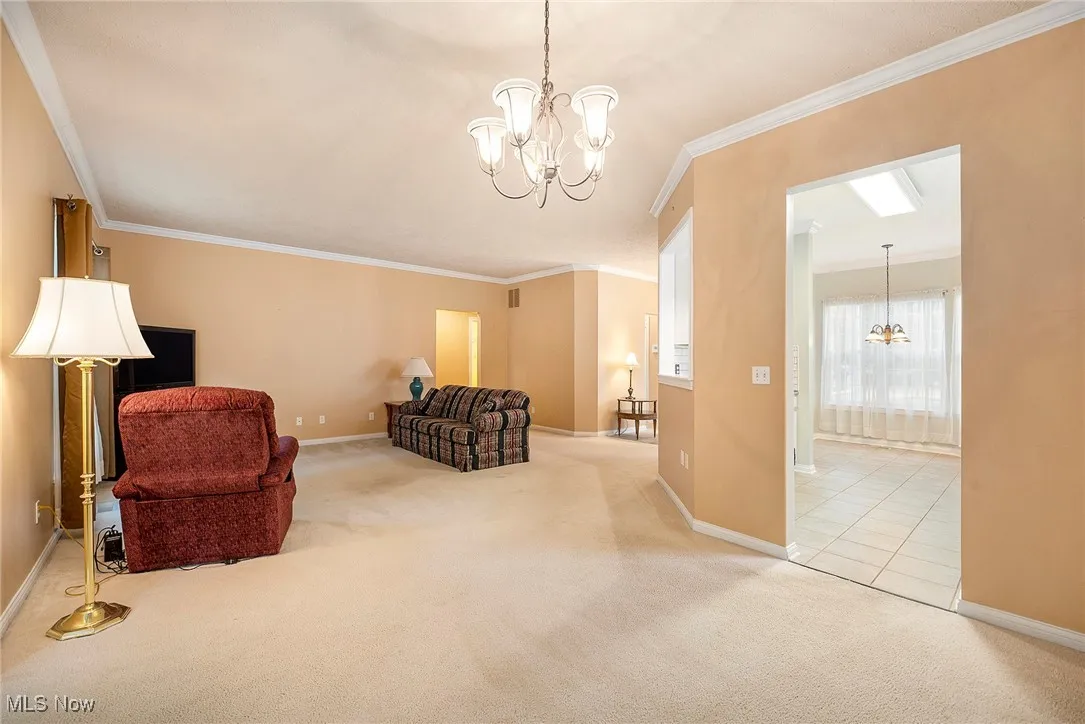 Living area featuring a chandelier, carpet flooring, and ornamental molding