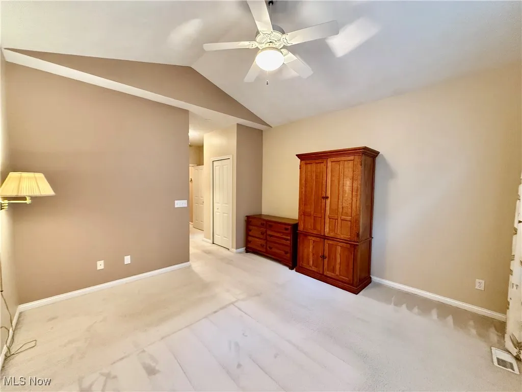 Unfurnished bedroom with vaulted ceiling, light carpet, a closet, and ceiling fan