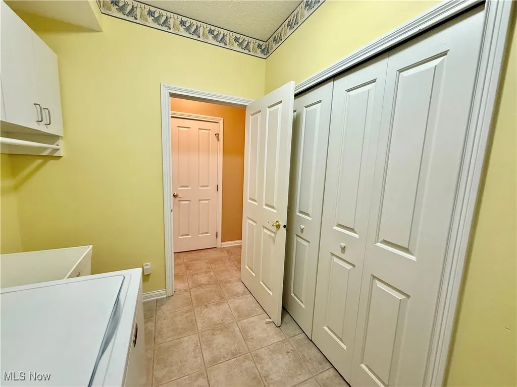 Laundry area featuring washer / dryer, cabinet space, and light tile patterned floors
