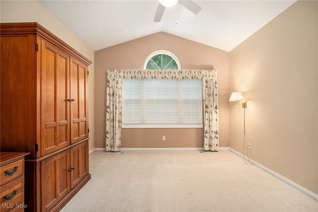 Unfurnished bedroom with vaulted ceiling, light carpet, and ceiling fan