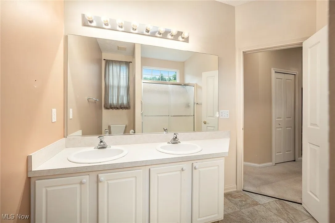 Full bath featuring double vanity and a stall shower