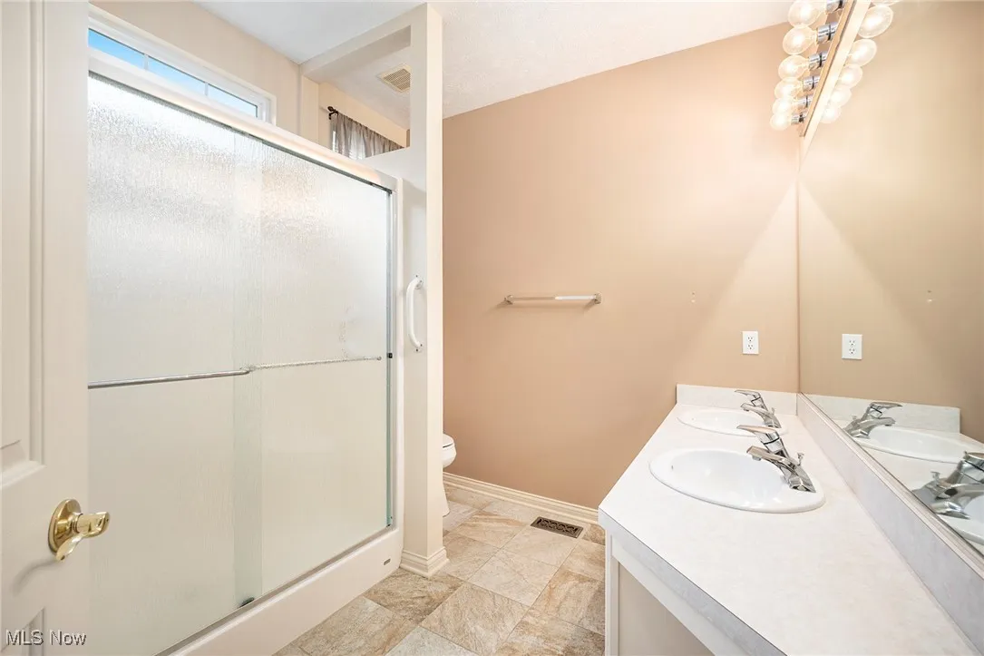 Full bathroom featuring a stall shower and double vanity