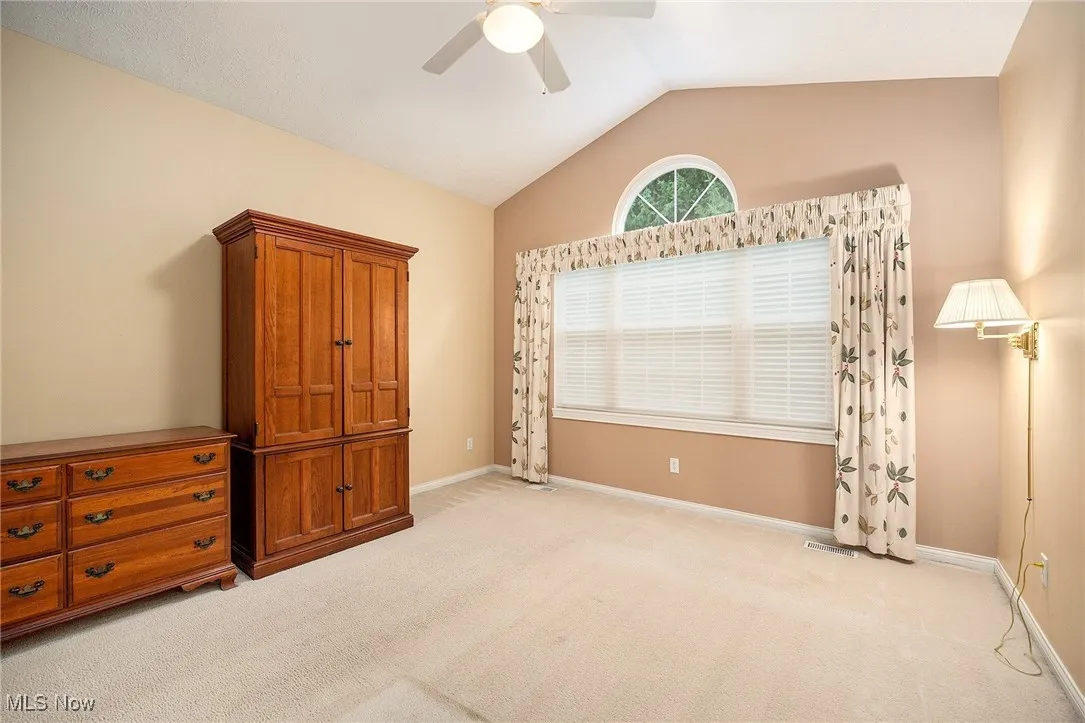 Unfurnished bedroom with vaulted ceiling, carpet floors, and a ceiling fan