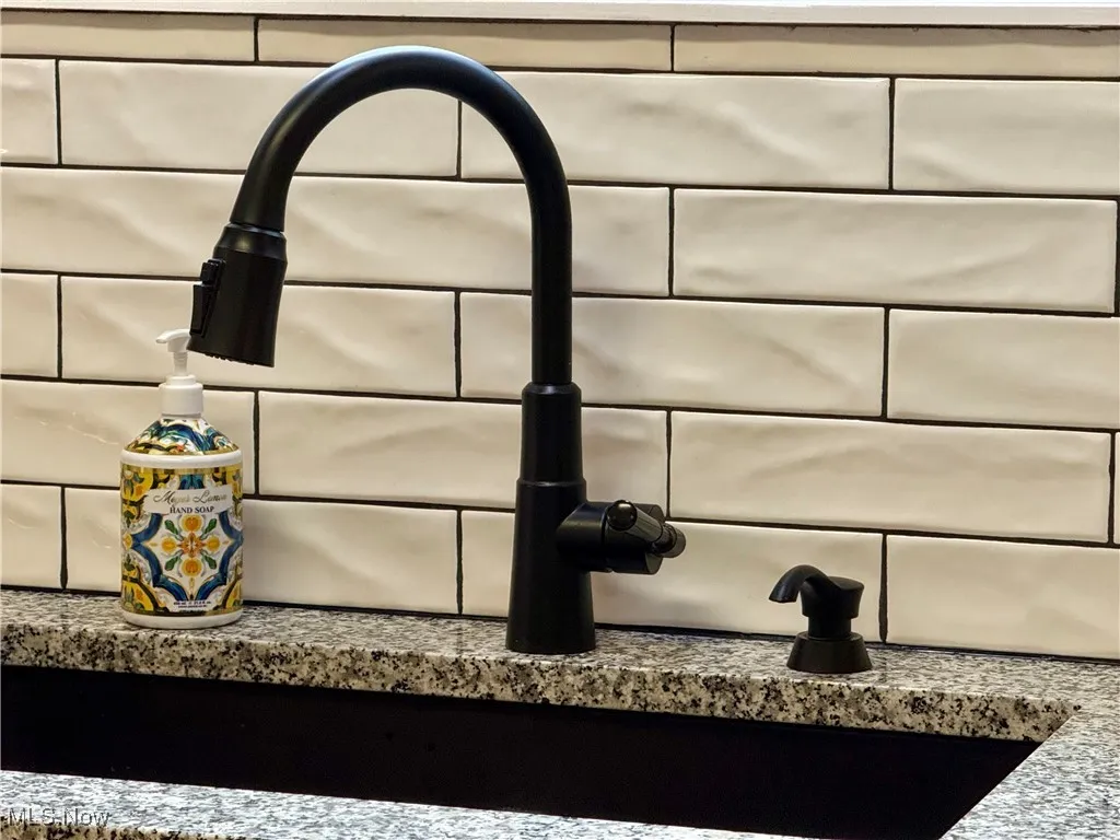 Detailed view of a sink and tasteful ceramic backsplash